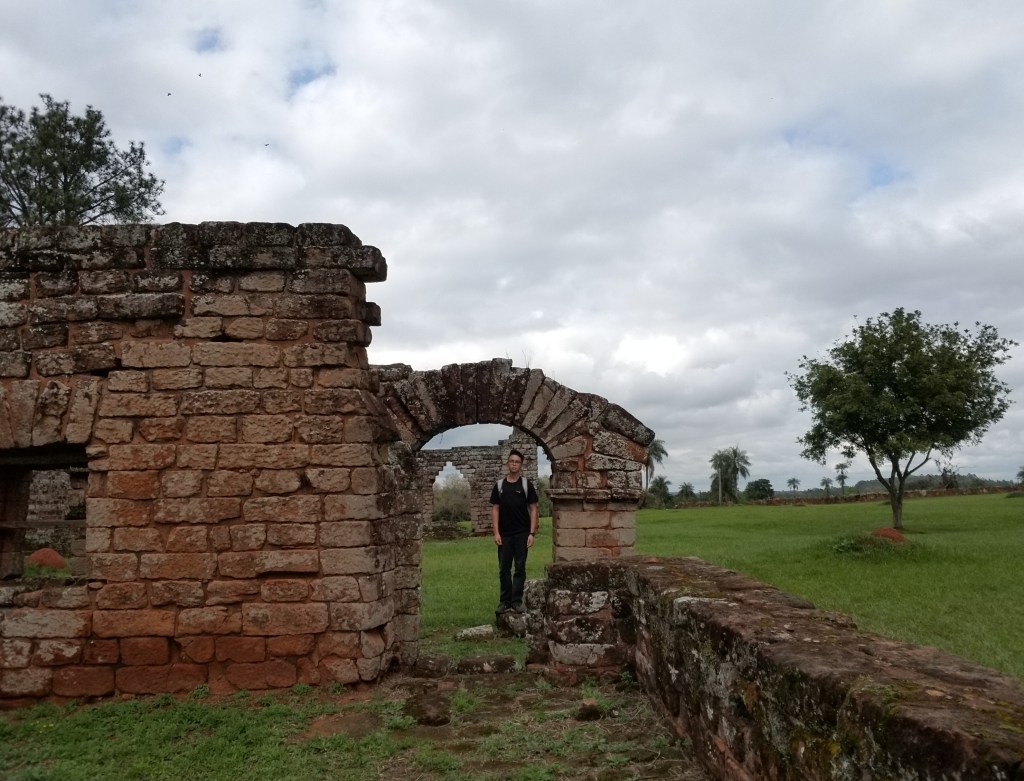 Elías standing under an arch at the Jesuit Mission of La Santísima Trinidad de Paraná
